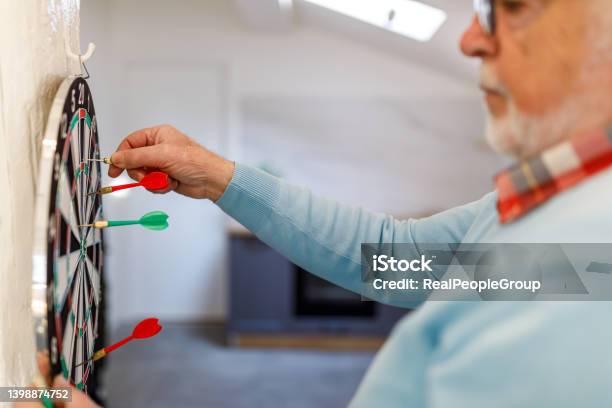 Senior Man Playing Darts At Home Stock Photo - Download Image Now - Dart, Darts, Holding