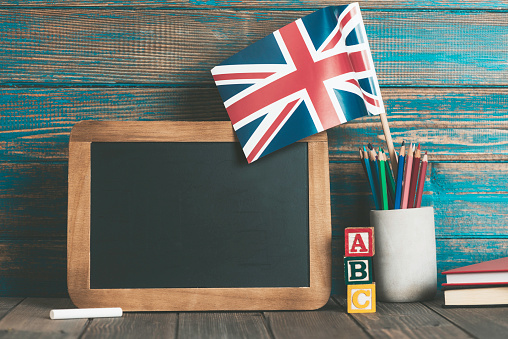 British flag in a pen holder, blackboard with a white chalk and A-B-C toy blocks representing education system in the UK.