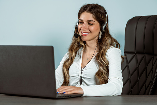 Female customer representative solving all problems with her laptop while having a conversation with headphones.