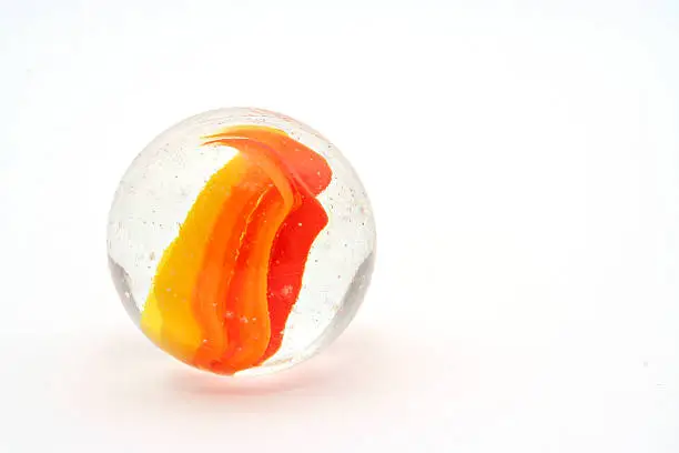 Photo of A clear and orange marble on a white background