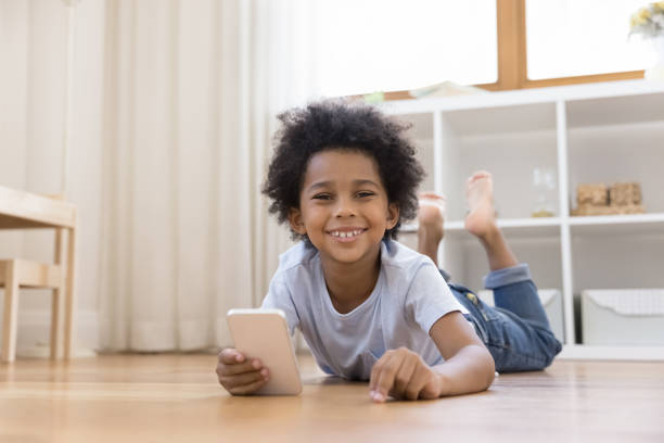 istock Little boy lying on floor inside warm nursery with smartphone 1398877785