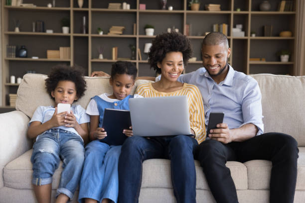 istock African couple with kids sit on sofa with diverse gadgets 1398877795