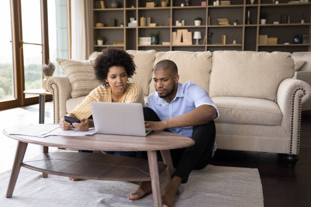 pareja africana seria que paga facturas en línea, calcule los gastos en casa - home finances couple computer african ethnicity fotografías e imágenes de stock