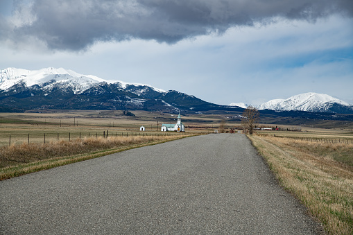 Montana rural highway headed toward snow capped Mountains. This is northwestern USA.