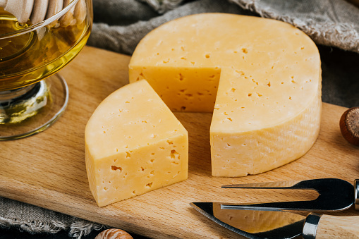 Cheese dish with organic cheeses, fruits, nuts on a wooden background. Delicious cheese snack