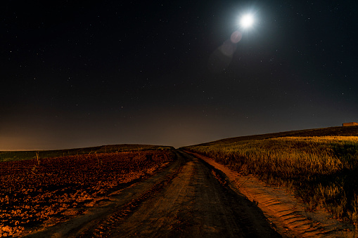 kırsal alanda bulunan köy yolunun dolunay ve yıldızlar altında gece görüntüsü uzun pozlama ile fotoğraflanmıştır. full frame makine ile çekilmiştir.