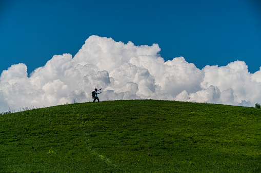 yeşil tepe arkasında yükselen beyaz bulutlar önünde sanal gerçeklik gözlüğü takmış adam. yeşil renk, mavi renk ve beyaz renk uyumu full frame makine ile çekilmiştir.