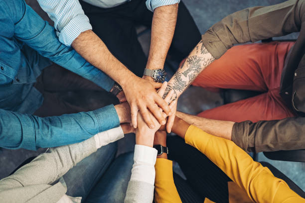 Team motivation Group of people stacking hands in a circle hands clasped stock pictures, royalty-free photos & images