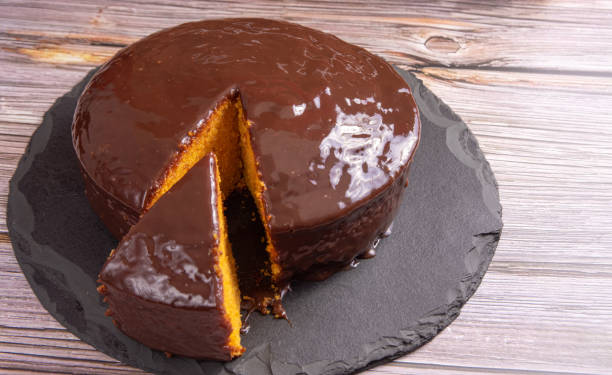 istock Sliced carrot cake, covered in chocolate on stone surface over rustic wood, selective focus. 1398879873