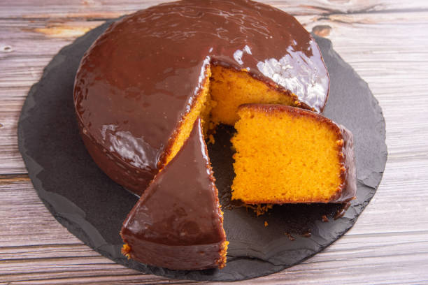 istock Sliced carrot cake, covered in chocolate on stone surface over rustic wood, selective focus. 1398879877