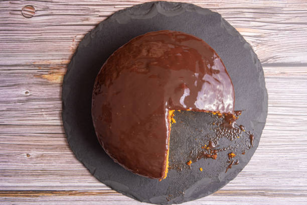 istock Sliced carrot cake, covered in chocolate on stone surface over rustic wood, selective focus. 1398879925