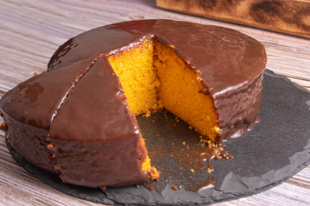 istock Sliced carrot cake, covered in chocolate on stone surface over rustic wood, selective focus. 1398879927