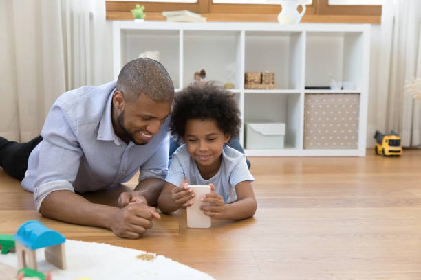 istock Cute boy his dad lying on floor with smartphone 1398880156