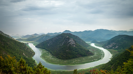 Overcast sky over the beautiful landscape. Aerial view of a river bend in the mountains