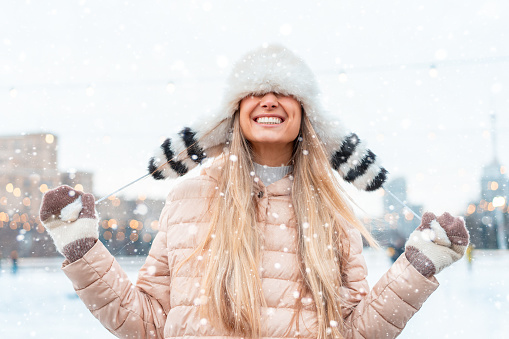 Happy winter time in big city charming girl standing street dressed funny fluffy hat. Enjoying snowfall, expressing positivity, smiling to camera, joyful cheerful mood, true emotions, Christmas mood