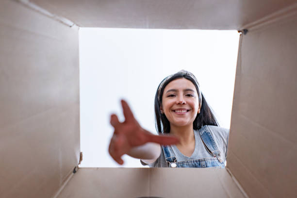 istock Beautiful woman doing into a new place unpacking boxes and grabbing something from box while smiling at camera 1398882504