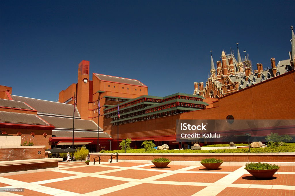 Modern architecture mixed with old architecture View of the courtyard of the British Library, London, with the gothic towers of St Pancras Station peeping over the top at the right. Space for text in the clear blue British Library Stock Photo