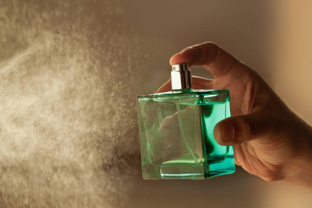 mão do homem pulverizando perfume de luxo em um fundo leve. - perfume - fotografias e filmes do acervo