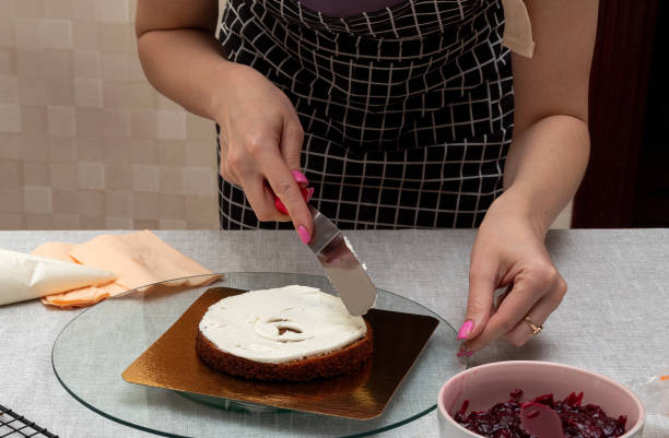 istock Leveling the cream on the sponge cake with spatula. There is bowl with stuffing on the table. The process of making cake. Selective focus. Picture for articles about food, confectioners. 1398888660