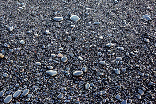 wet dark pebbles and rocks on the ocean coast. black reynisfjara beach in Iceland