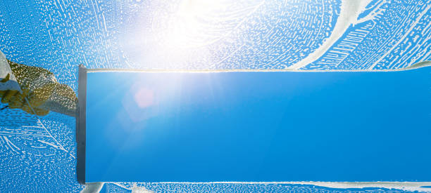 istock Window cleaner cleaning window with squeegee and wiper on a sunny day with a bright blue sky 1398893109