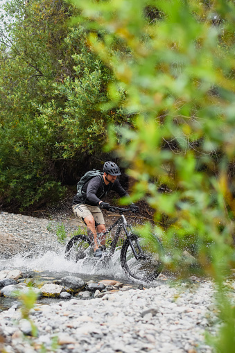 A mountain biker riding through a stream of mountain water on a downhill trail
