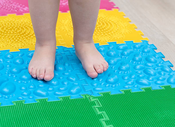 people. children's small legs stand on multi-colored massage rugs. health concept. soft focus. close-up. - plattfot bildbanksfoton och bilder