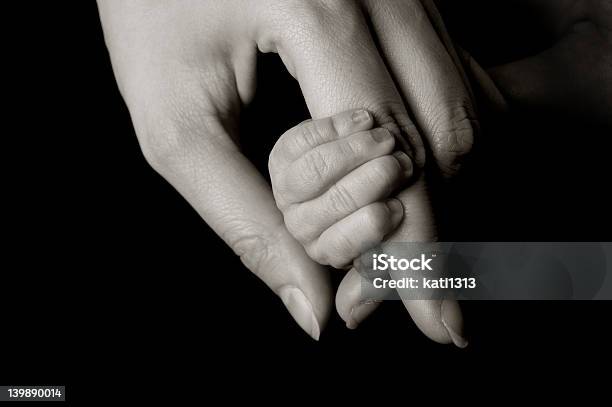 Hand Holding A Tiny Babys Hand On Isolated Black Background Stock Photo - Download Image Now