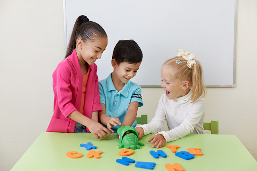 Preschool children playing with alphabet letters on a table