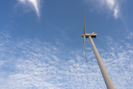 Wind turbine under blue sky and white clouds