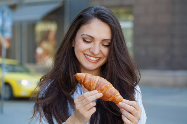 istock Young woman eating a croissant 1398909250