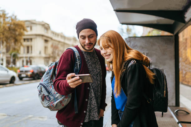 istock Friends looking at cellphone at bus stop 1398909309