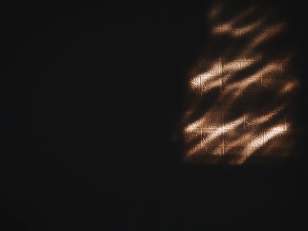 A sharp shadow cast on a smooth surface creates an abstract geometric pattern. The contrast between light and dark adds depth and intrigue. This minimalist composition is suitable for artistic or design contexts.