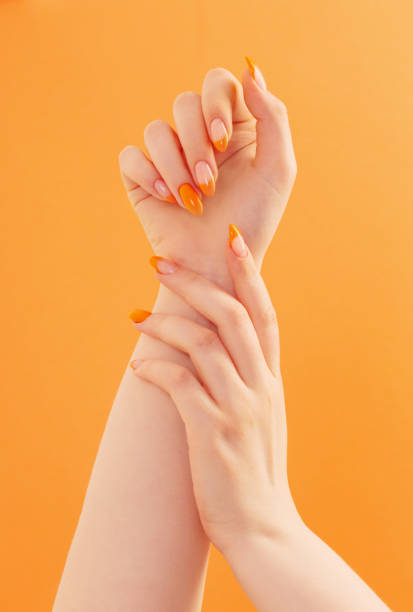 female hand with manicure on orange background stock photo