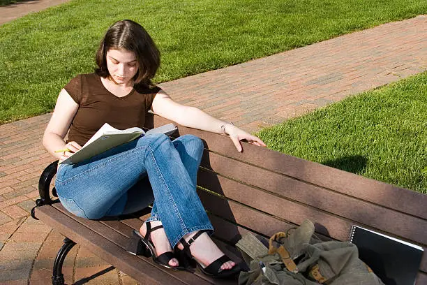 Photo of Pretty brunette college student reclining on bench