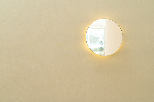 Small round looking glass mirror on wall background. Reflected round mirror