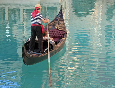 Venice, Italy - October 8th 2022:  Motorboat, probably a water taxi, crossing the path of a gondola with tourists in Canal Grande in the center of Venice