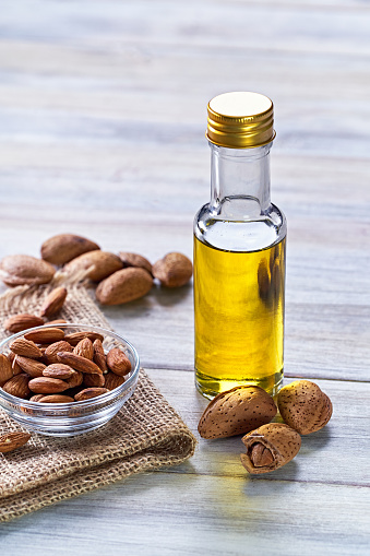 Close-up of almond oil in a bottle with almond seeds