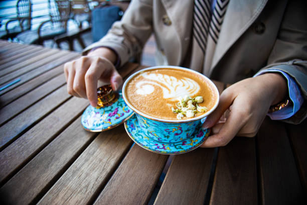 Hand holding cup of coffee on table