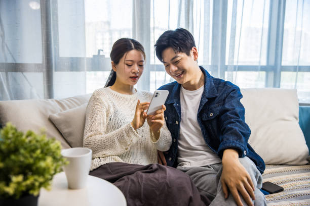 istock Young couple sharing social media with mobile phone together 1398928075