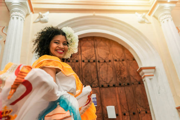 giovane donna meticcia con i capelli neri ricci fuori da una chiesa a leon nicaragua, indossa un tradizionale abito giallo guardando la macchina fotografica e sorridendo. concetto di cultura e tradizione della danza - danza tradizionale foto e immagini stock