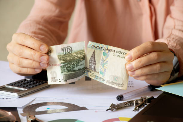 istock Women's hands tear ten rubles at a table with reports, default in Russia due to sanctions, collapse of the ruble 1398931312