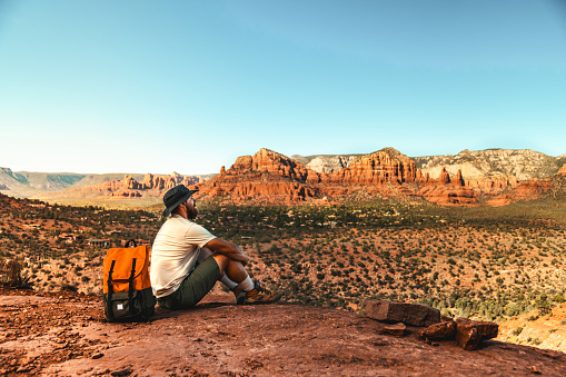 A young man with a backpack in canyon resting and enjoying the view