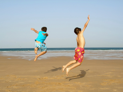 Two boys jumping of joy on the beach