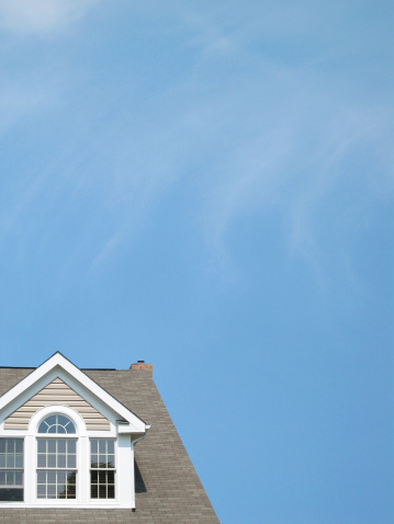 roofline of a residential house against blue sky background.