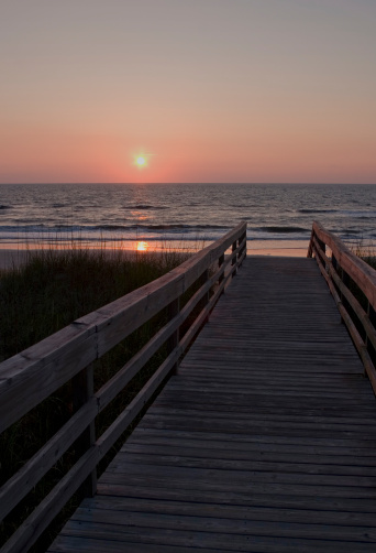 View of sunrise on the beach from wooden walkway