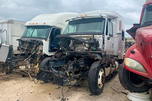 Three broken trucks in junk yard after accident, discarded salvage cars with crashed engines. Outdoor park with automobile wreckage parts debris