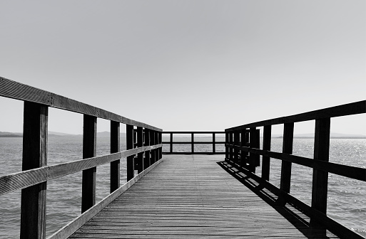 Long wooden pier over sea in black and white photo