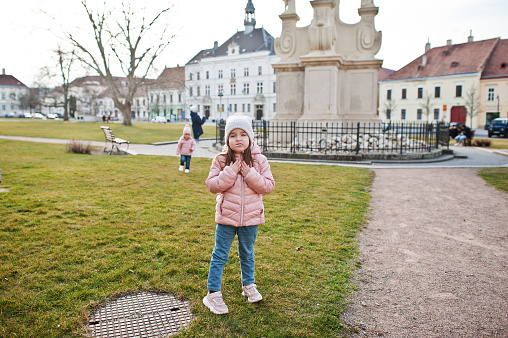 Baby girl with lollipop, wear pink jacket walking at Valtice town, Czech Republic.