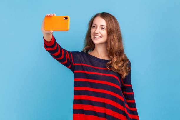 istock Woman with happy expression making selfie or broadcasting livestream, looking at phone display. 1398942090